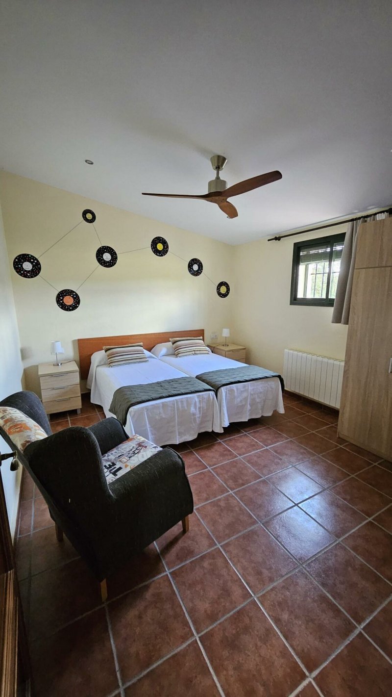 Habitación doble con dos camas, suelo de barro, ventilador de techo y vinilos decorativos