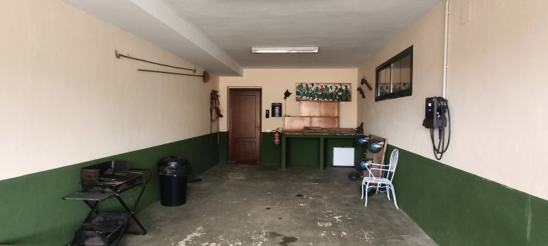 Garaje con paredes bicolores verdes, contador eléctrico, mostrador de madera y puerta interior