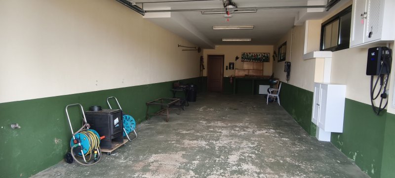 Garaje amplio con paredes bicolor verde y beige, manguera enrollada y herramientas